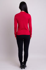 Women's red long-sleeve mock neck sweater worn with black pants. Made with sustainable and natural fibers, fair-trade. Back view.