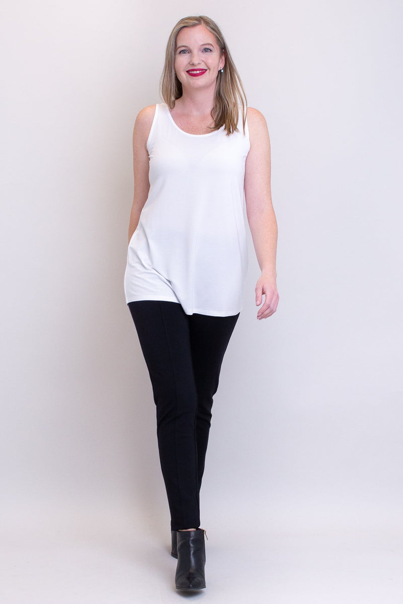 Women's plus-size casual white flowy tank top with wide shoulder strap and U-neckline, worn with black pants and boots.
