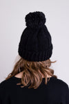 Women's black knit toque wool hat with pompom.