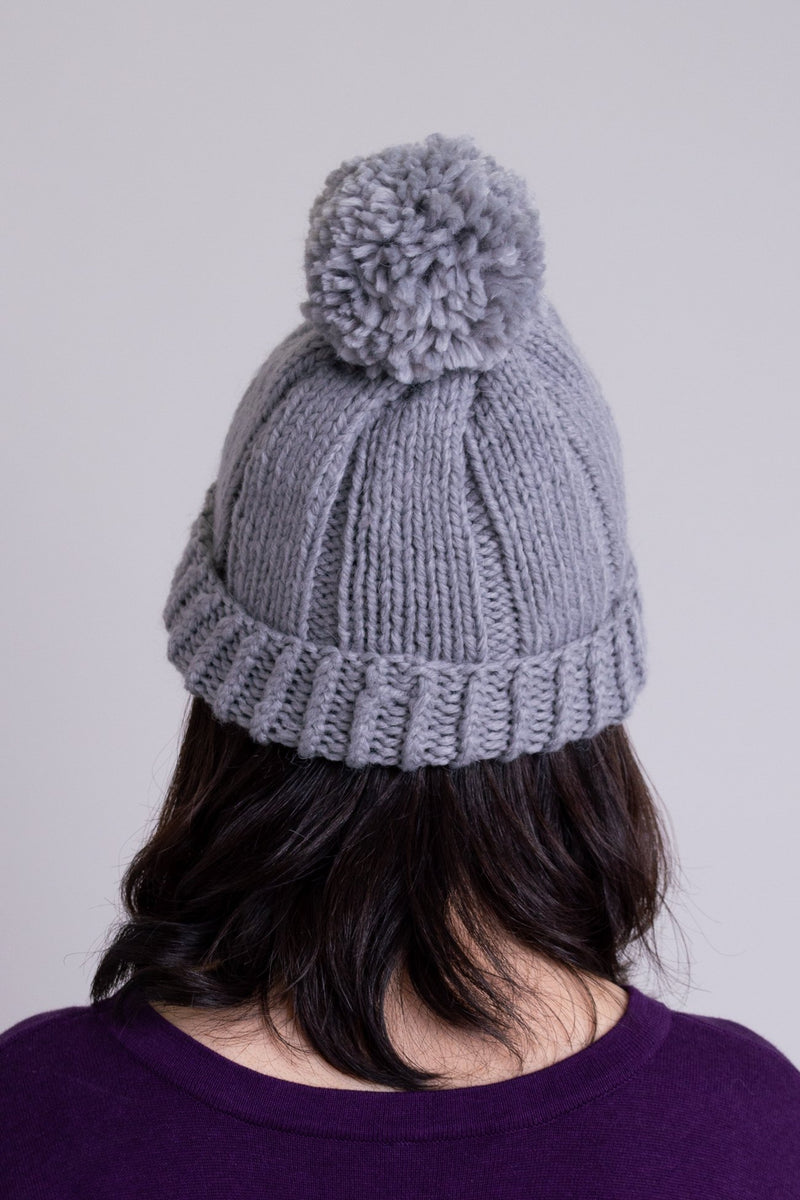 Women's grey knit toque wool hat with pompom.
