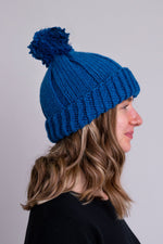 Women's teal blue knit toque wool hat with pompom.