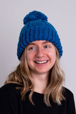 Women's teal blue knit toque wool hat with pompom.